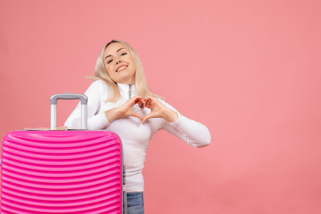 视图正面图年轻女士站在粉色手提箱后面做心形标志站立心成人