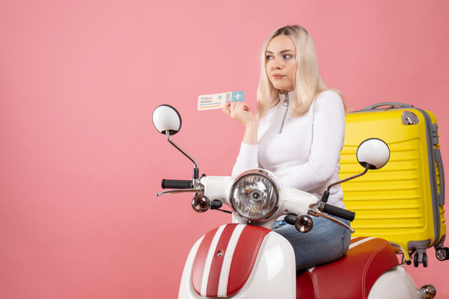 年轻女士前视图骑着轻便摩托车的年轻女士拿着机票成人前面轻便摩托车