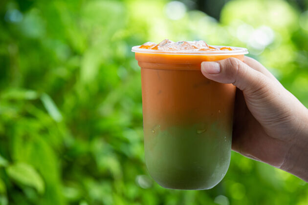 服务泰国冰茶与绿茶混合在木制表面塑料冷美味