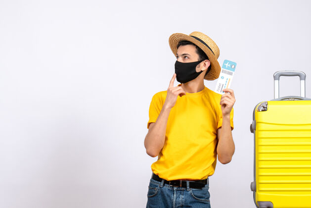 正面正面图身穿黄色t恤的年轻游客站在黄色手提箱旁举着机票人视图T恤