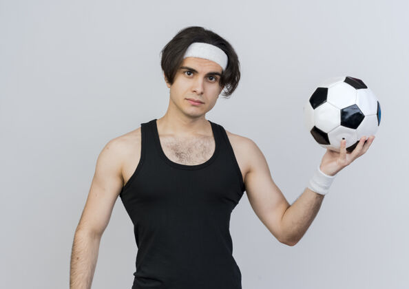 足球穿着运动服 头戴足球带的年轻人站在白色的墙上 严肃地看着前面穿着运动脸