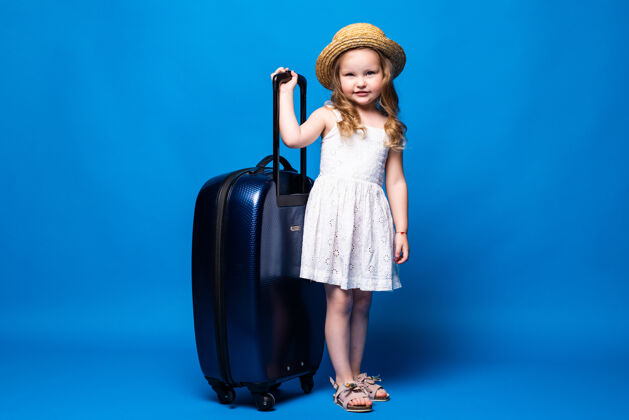手提箱美丽的小女孩和行李隔离在蓝色墙上的全长肖像周末出国旅行的乘客航空旅行的概念行李度假肖像