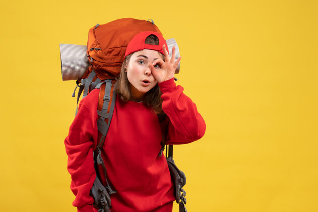 成人正面图：年轻的女旅行者 背着背包 眼睛上贴着“OK”标志眼睛背包前面