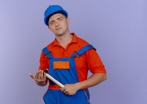 背景高兴的年轻男性建筑工人穿着制服和安全帽手持铁锤男性紫色请拿着
