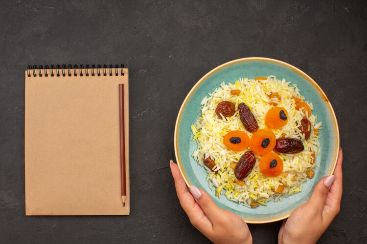 葡萄干顶视图美味的煮熟普洛夫米饭与不同的葡萄干内板上的灰色表面铅笔晚餐不同