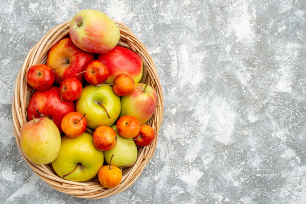 农产品顶视图塑料柳条篮红色和黄色的苹果和李子在灰色的桌子左侧壁板食品餐桌
