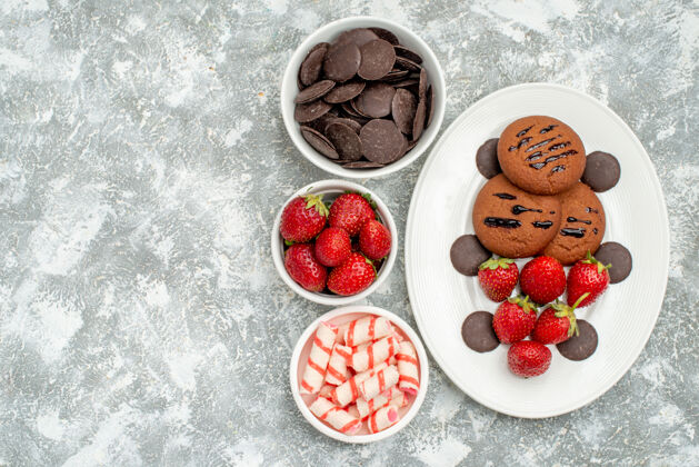巧克力俯视巧克力饼干草莓和圆形巧克力在白色椭圆形盘子和碗糖果草莓和巧克力在地面的右侧盘子可食用水果浆果