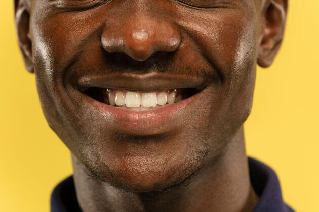 公司黄色摄影棚背景上的非洲裔美国年轻人的特写肖像美丽的男模 保持良好的皮肤人类情感的概念 面部表情 销售 广告看起来平静和微笑成功广告表达