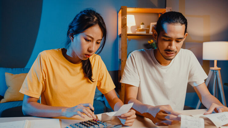 悲伤强调亚洲夫妇男女使用计算器计算家庭预算金钱财务问题
