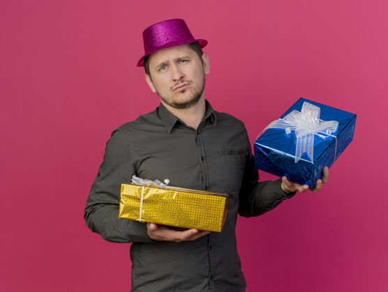 男人一个戴着粉色帽子 拿着礼品盒 孤零零地站在粉色地板上的年轻人戴着盒子派对