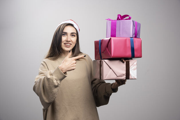 礼物年轻女子指着三盒圣诞礼物红色女孩盒子