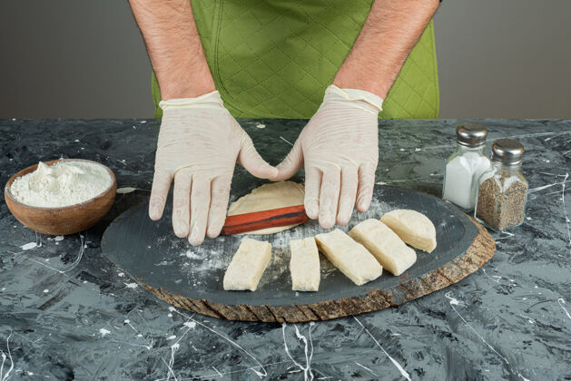 烹饪男人戴着手套在大理石桌上做面团手工制作小麦面包师