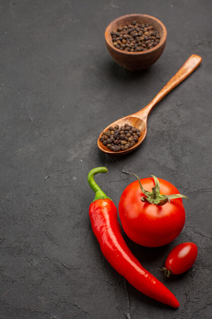食物顶视图一碗黑胡椒和番茄红辣椒和一个樱桃番茄在黑色背景上辣椒背景樱桃