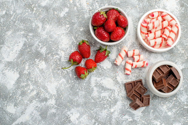 食品顶视图碗草莓巧克力糖果和一些草莓巧克力糖果在灰白色马赛克地面右侧浆果水果壁板