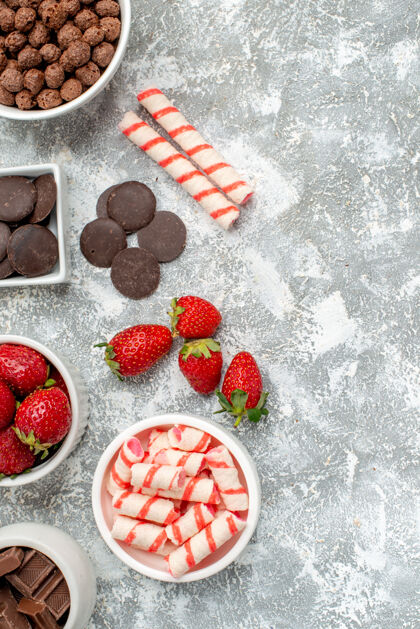 浆果顶视图碗与糖果草莓巧克力谷类糖果和一些草莓糖果巧克力在灰白色的地面左侧蓝莓左边食物