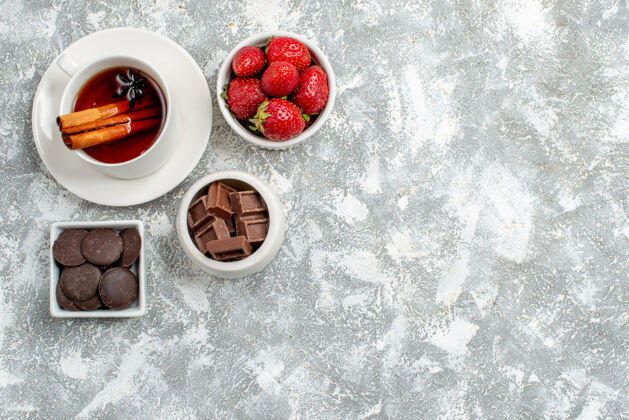 磨碎顶视图碗草莓和巧克力和肉桂茴香种子茶在左上角的灰白色地面茶种子甜点