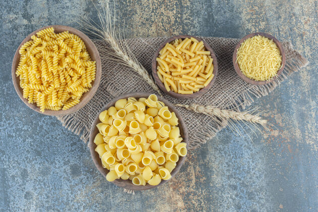 美味四种碗里的意大利面 在大理石背景上烟斗粉丝小麦