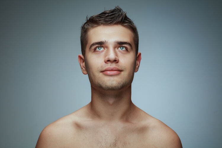 头发隔离在灰色工作室背景上的赤膊青年的肖像白种人健康的男模抬起头来摆姿势男人的健康和美丽 自我护理 身体和皮肤护理的概念卫生年轻男性