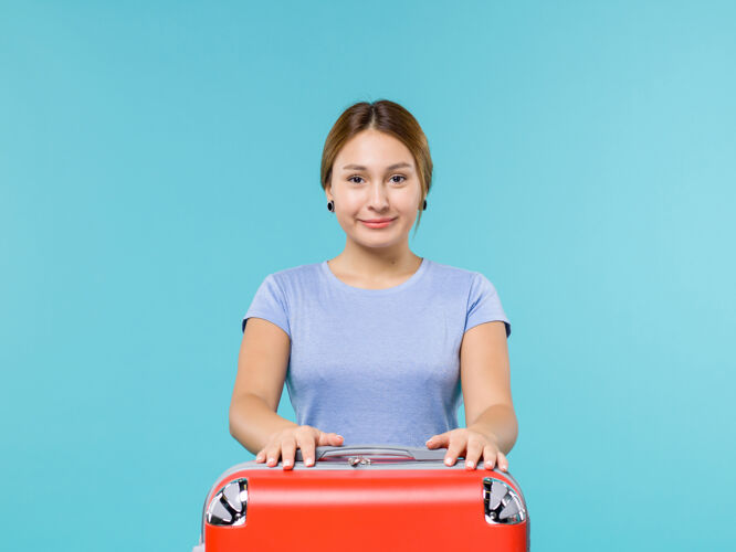 成人正面图：度假中的女性 带着她的红色袋子 在蓝色的背景上微笑 度假飞机旅行 航海旅行风景旅行前面