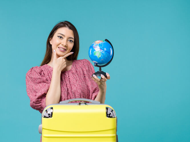 旅行前景度假女抱着小地球仪在蓝色背景上微笑海上旅行避暑女旅行度假假期女人地球
