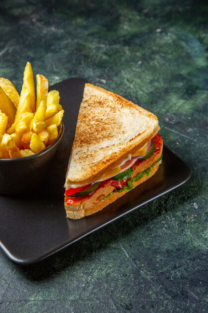 快餐前视图火腿三明治与炸薯条内板在黑暗的表面汉堡包土豆薯条