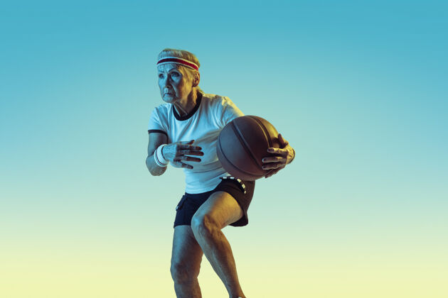 教练运动装的高级女性在渐变背景下打篮球 霓虹灯身材匀称的女性模特保持活跃运动 活动 运动 健康 自信的概念复制空间发球老年人球