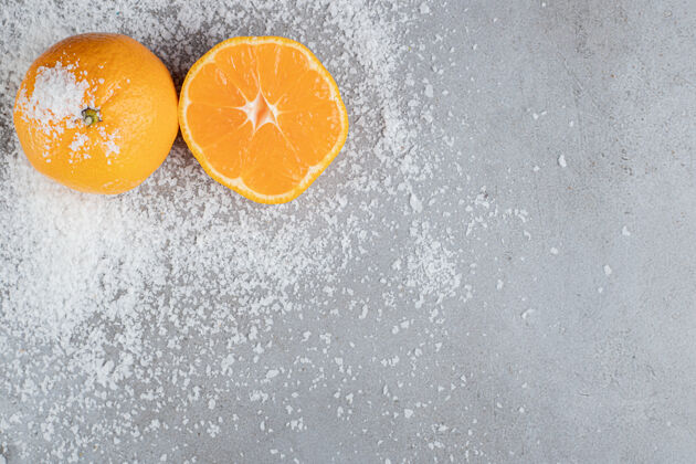 辛辣整个橙子和切成片的橙子放在撒在大理石表面的椰子粉里美味食品柑橘