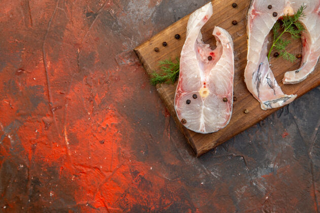 胡椒新鲜生鱼肉和胡椒粉在混合色表面左侧的木质砧板上的俯视图旧的壁板鸟舍
