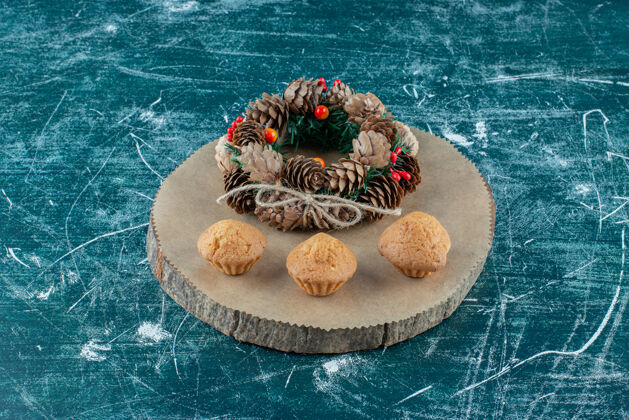 纸杯蛋糕大理石上有花环的美味松饼花环圣诞花环可口
