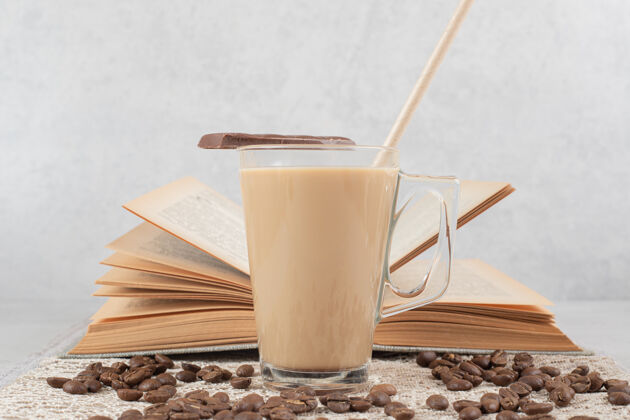 香气一杯咖啡加巧克力 书和咖啡豆放在粗麻布上咖啡一餐玻璃