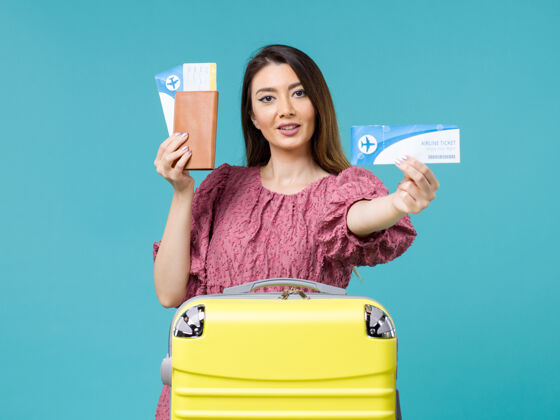 票前景度假中的女性手持蓝色背景的机票出海度假的女性夏天旅程旅行假期