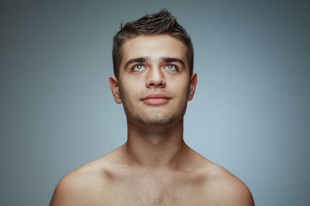 头发隔离在灰色工作室背景上的赤膊青年的肖像白种人健康的男模抬起头来摆姿势男人的健康和美丽 自我护理 身体和皮肤护理的概念卫生年轻男性