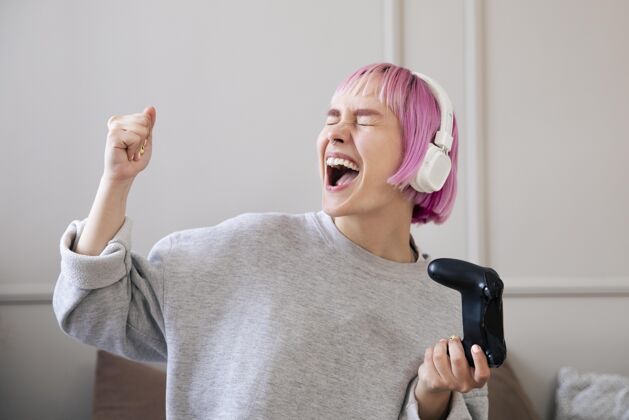娱乐粉红色头发的女人在玩电子游戏在线室内房子