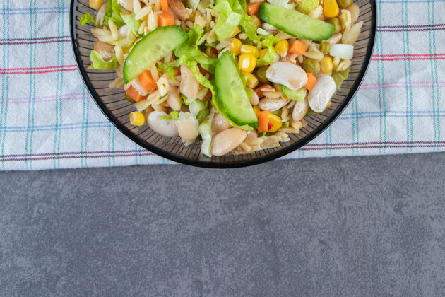 美味两碗蔬菜沙拉和胡萝卜片放在茶巾上 放在大理石表面饭白豆沙拉
