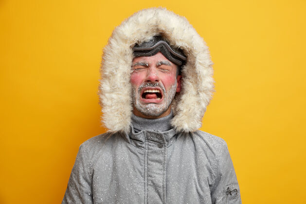 外套垂头丧气的男人哭着 不开心 穿着冬装 滑雪后感觉很冷 脸上涂着白霜 戴着滑雪镜站立冰冻沮丧