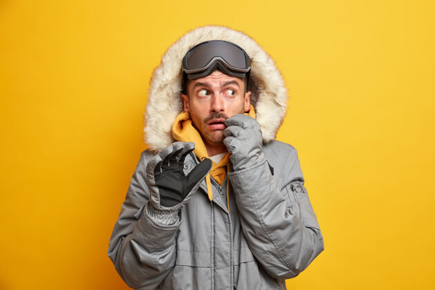 风景害怕的欧洲男人穿着外套 带着毛皮风帽 在山上休息 享受极限运动 在寒冷的季节有积极的休闲表情印象滑雪者