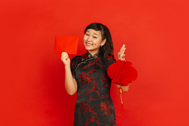 祝福2020年中国新年红色背景上的亚洲少女肖像穿着传统服装的女模特看起来很高兴装饰和红包庆祝 节日 情感女孩照明手
