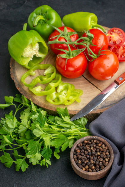 食品新鲜西红柿和青椒在木板上的垂直视图黑色表面上的绿色捆绑饮食生菜香草