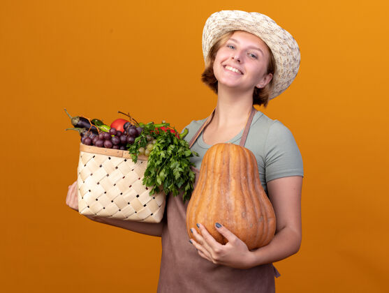 帽子年轻的斯拉夫女园丁戴着园艺帽 手里拿着菜篮 手里拿着桔子上的南瓜斯拉夫人园艺蔬菜
