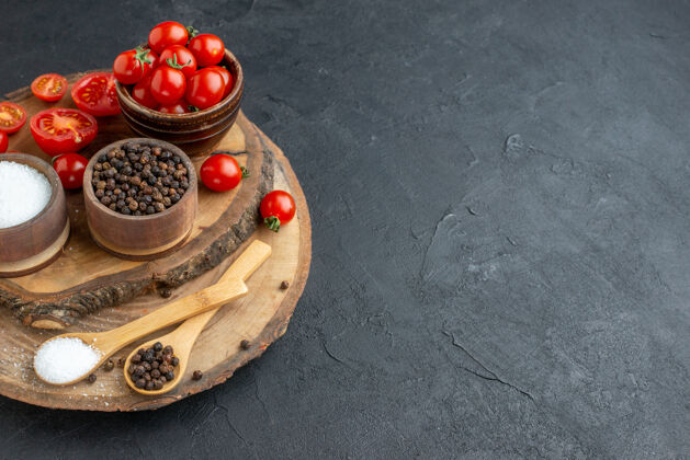 香料侧视图新鲜番茄和香料在木板上的黑色表面美味壁板浆果