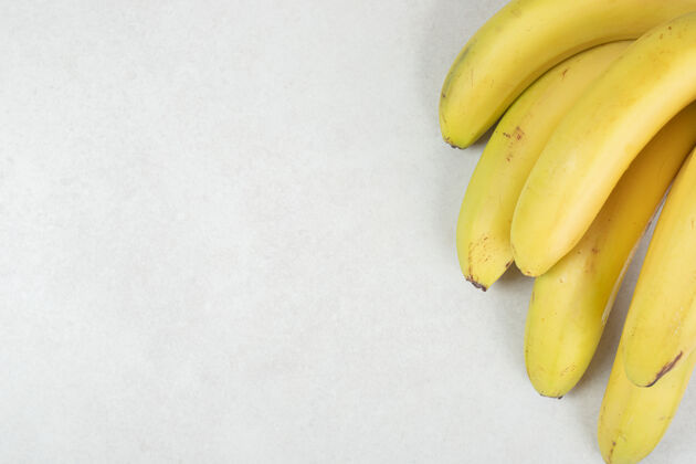 一餐灰色表面上的一堆黄色香蕉可口配料水果