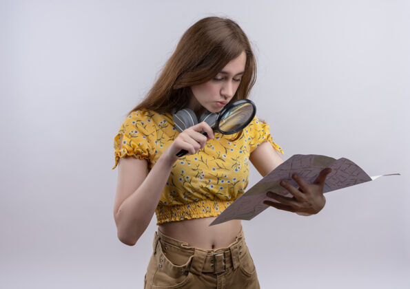 女孩困惑的年轻女孩拿着地图 通过放大镜看着它在孤立的空白空间与复印空间玻璃持有年轻