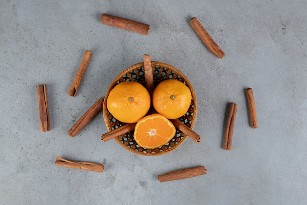 肉桂大理石桌上放着一小篮橘子和肉桂美味橙子切