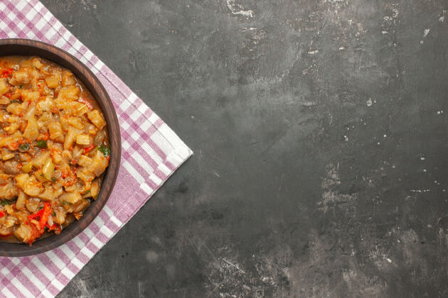 深色顶视图烤茄子沙拉碗在粉白色格子表面桌布午餐餐
