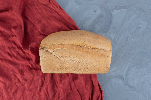 可口放在大理石桌上的红桌布上的面包面包面团可口