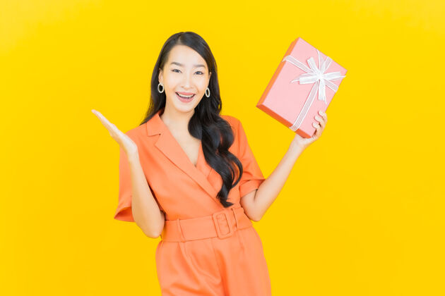 粉色肖像美丽的亚洲年轻女子微笑红色礼盒上的黄色模特礼物庆典