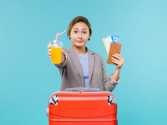 果汁正面图：度假中的女性拿着新鲜的果汁和机票在蓝色的海底度假飞机上旅行假期旅程人