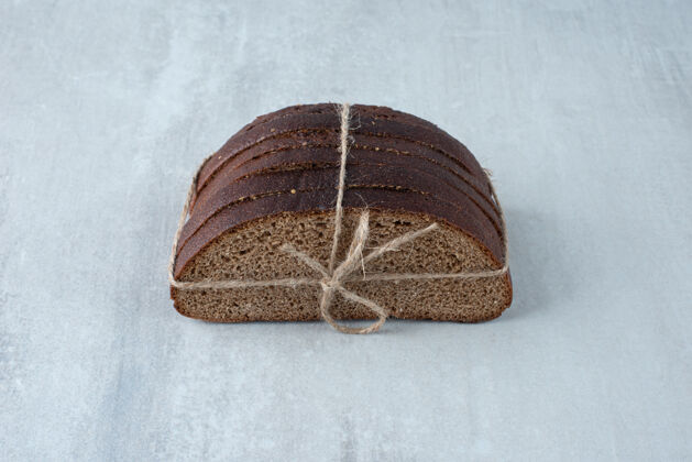 面包房黑麦面包用绳子绑在石头表面美味面包切片