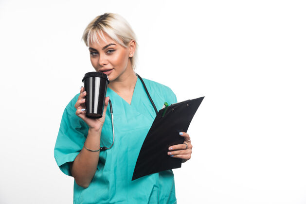 医生女医生在白墙上喝咖啡文件夹拿着医院