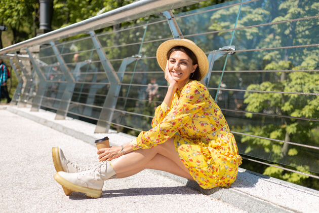 积极穿着黄色夏装 戴着帽子 喝着咖啡 享受阳光的女人的户外肖像咖啡芳香城市